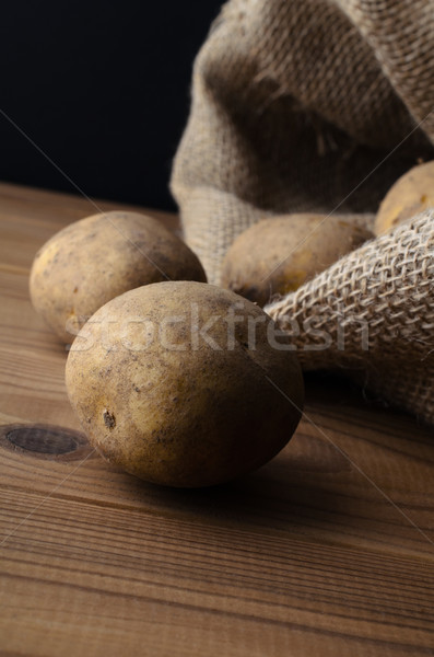 Potatoes Spilling from Sack on to Wood Plank Table Stock photo © frannyanne