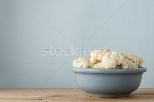 Raw Cauliflower in Bowl on Wood Plank Table with Blue Background Stock photo © frannyanne