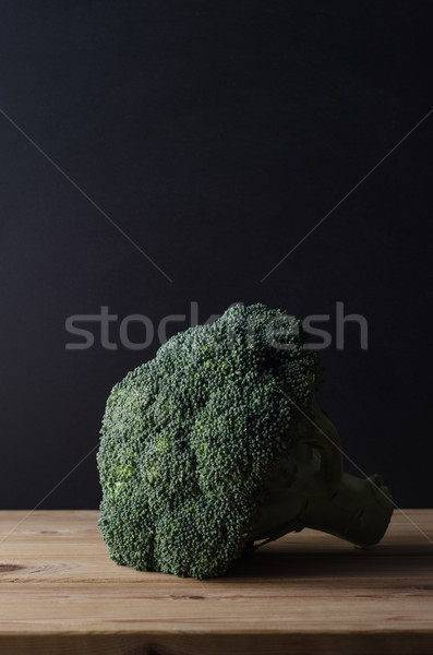Head of Dark Green Broccoli on Wood Plank Table against Black Ba Stock photo © frannyanne