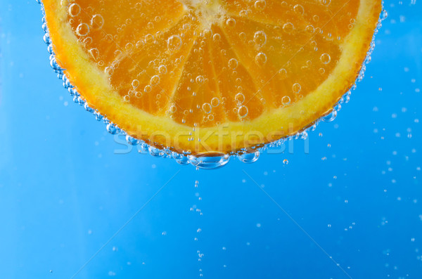 Friss narancsszelet pezsgő kék víz közelkép Stock fotó © frannyanne