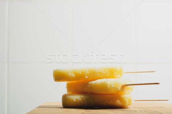 Yellow Ice Lollies Stacked on Wood with White Tiled Background Stock photo © frannyanne