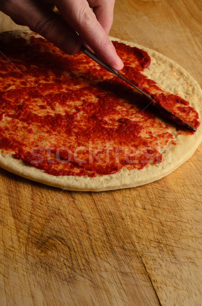 Hand Spreading Tomato on Pizza Base Stock photo © frannyanne