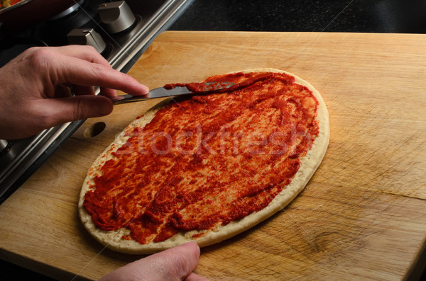 Hand Spreading Tomato Puree on Pizza Base Stock photo © frannyanne