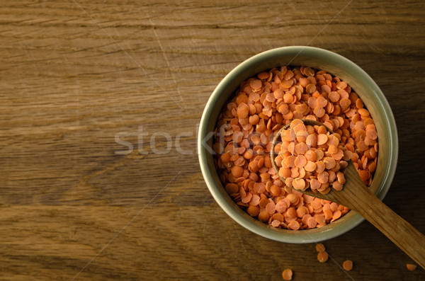 Stock photo: Overhead of Spoon Raising Red Lentils from Green Bowl on Oak Woo