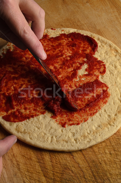 Hand Spreading Tomato Puree on Pizza Base Stock photo © frannyanne