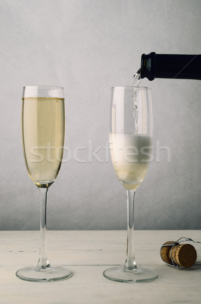 Pair of Fluted Champagne Glasses Being Filled on Wood Plank Tabl Stock photo © frannyanne