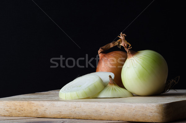 Whole and Sliced Onions on Chopping Board with Black Background Stock photo © frannyanne