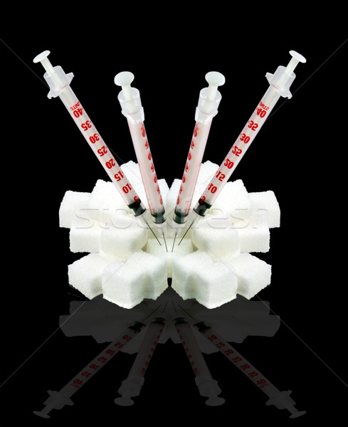   Insulin syringes stuck into the lump sugar. Isolated on a black background. Stock photo © g215