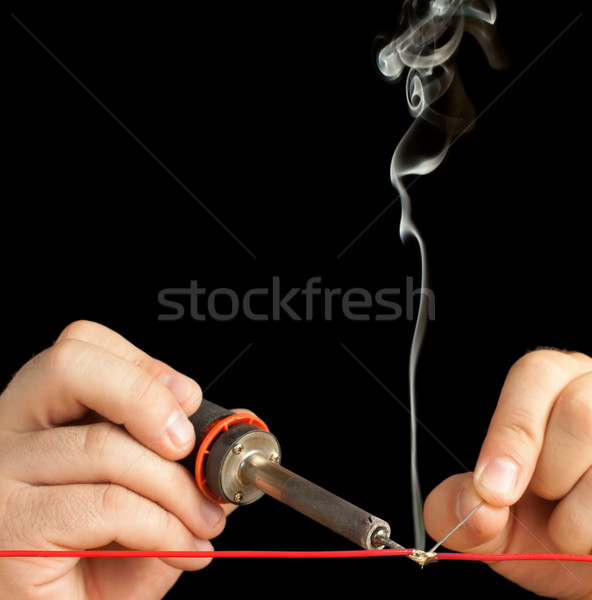 Technician soldering two wires together on a black background. Stock photo © gabes1976