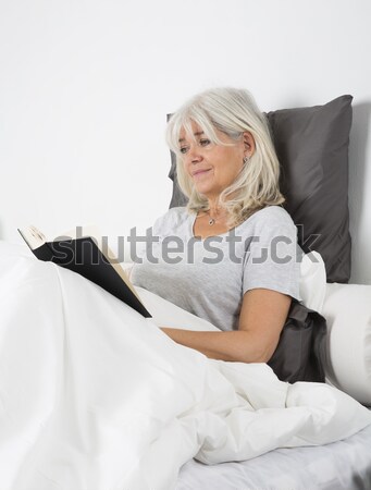 Mid Age woman with a laptop in bed Stock photo © gemenacom