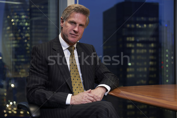 Homem de negócios sessão tabela sala de reuniões olhando câmera Foto stock © gemphoto