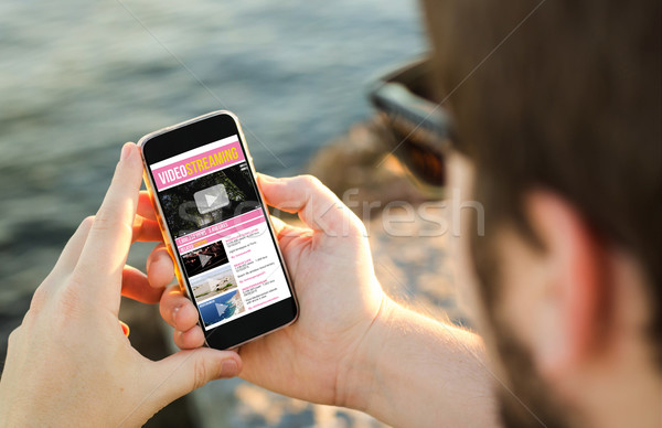 Człowiek telefonu komórkowego wybrzeża oglądać filmy smartphone Zdjęcia stock © georgejmclittle