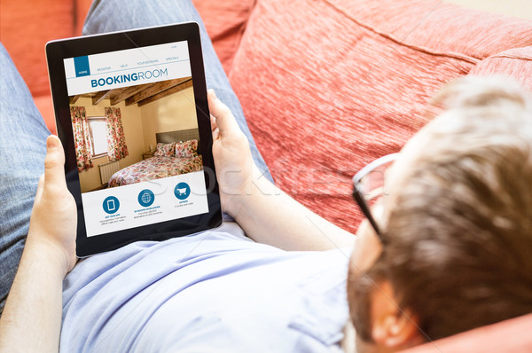hipster on the sofa with booking web at tablet Stock photo © georgejmclittle