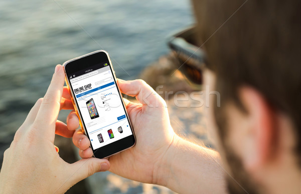 Man mobiele telefoon kust winkel online smartphone Stockfoto © georgejmclittle