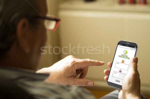 Portrait of a mature man translating text in a mobile phone Stock photo © georgejmclittle