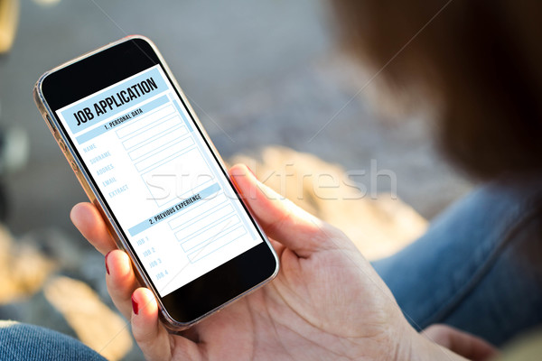 woman sitting in the street holding her smartphone with job appl Stock photo © georgejmclittle