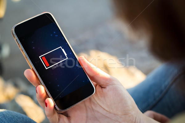 woman sitting in the street holding her smartphone with low batt Stock photo © georgejmclittle