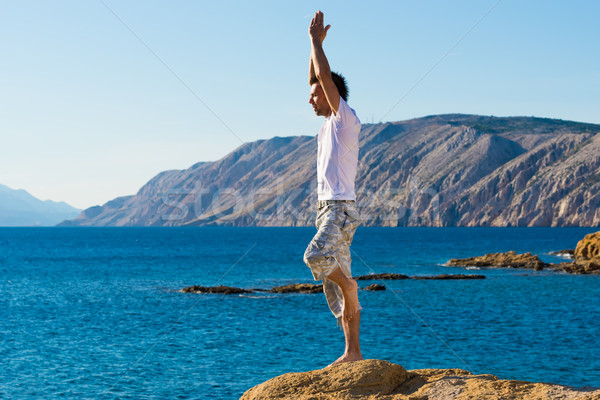 Handsome man in a yoga position on the beach Stock photo © Geribody