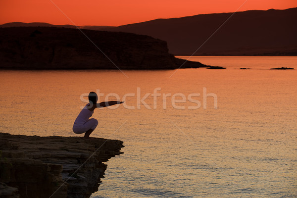 Silhouette of a woman doing yoga on the beach at sunset Stock photo © Geribody