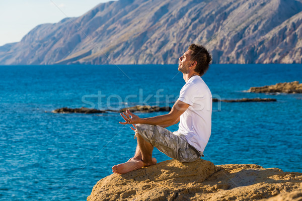 Handsome man in a yoga position on the beach Stock photo © Geribody