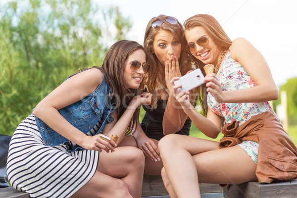 3 beautiful girlfriend watch the funny photos taken at  Stock photo © Geribody