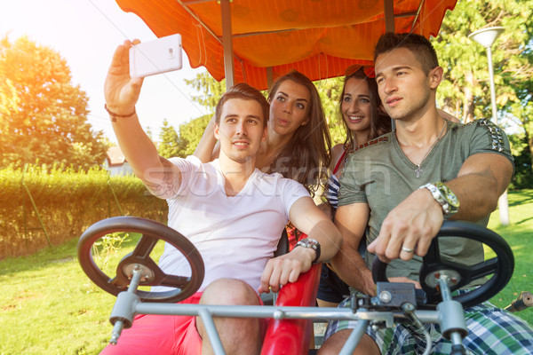 Four young people in a four-wheeled bicycle, they do selfie Stock photo © Geribody