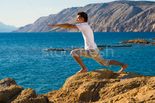 Handsome man in a yoga position on the beach Stock photo © Geribody