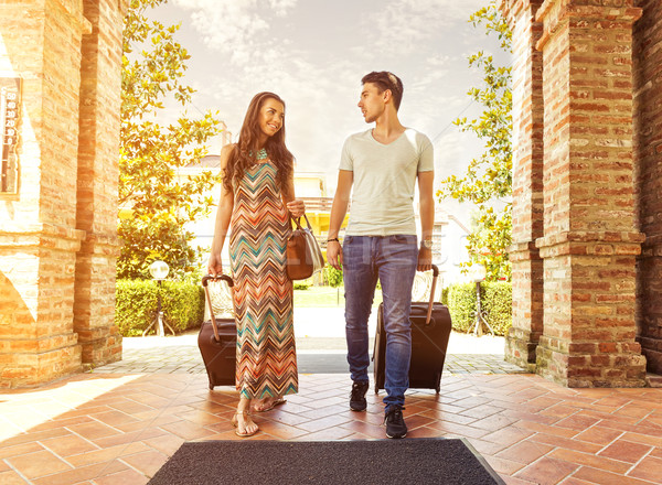 Young couple standing at hotel corridor upon arrival, looking for room, holding suitcases Stock photo © Geribody