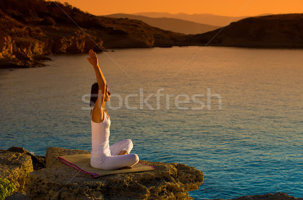 Woman making yoga figure on the beach at beautiful sunrise Stock photo © Geribody