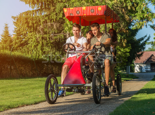 Four young people in a four-wheeled bicycle Stock photo © Geribody