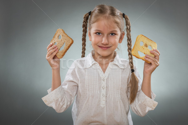Beautiful little girl with a happy bread in one hand and the other hand holding a sad slice of bread Stock photo © Geribody