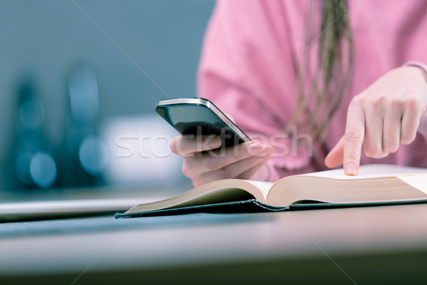Woman holding mobile phone while reading book Stock photo © Giulio_Fornasar