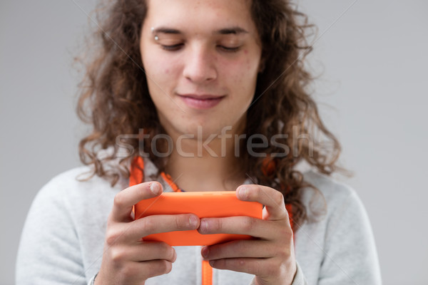 Zdjęcia stock: Długowłosy · młody · człowiek · pomarańczowy · smartphone · uśmiechnięty · technologii