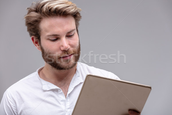 Attractive young man reading on a tablet-pc Stock photo © Giulio_Fornasar