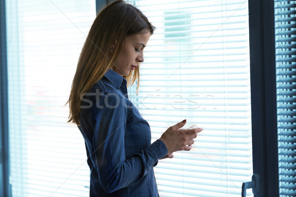Young woman standing by window with mobile phone Stock photo © Giulio_Fornasar