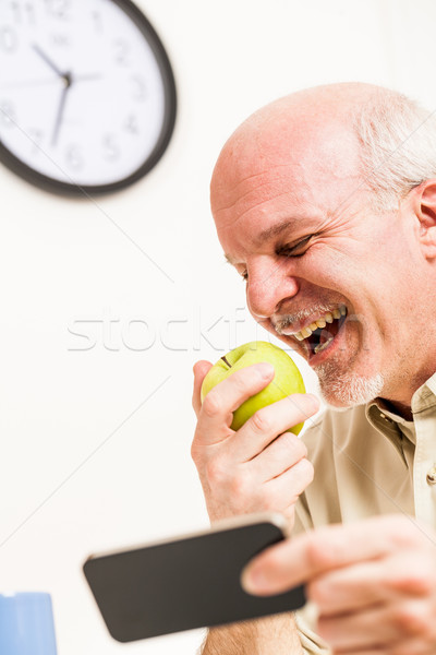 Happy senior man eating and using phone at work Stock photo © Giulio_Fornasar