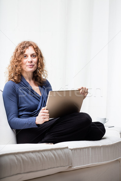 Cheerful woman sitting on sofa with tablet Stock photo © Giulio_Fornasar