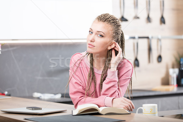 Stock photo: woman in her kitchen reading a book
