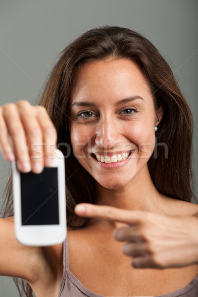 Happy attractive woman pointing to her mobile Stock photo © Giulio_Fornasar
