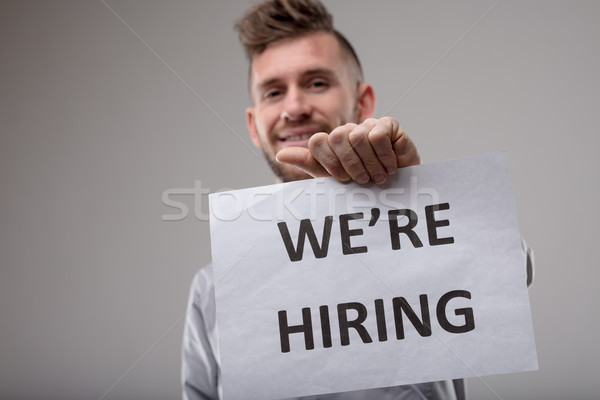 Smiling man holding up a sign We're Hiring Stock photo © Giulio_Fornasar