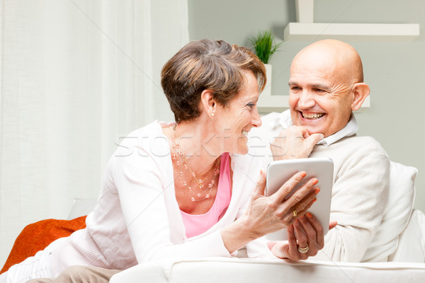 Husband and wife chuckling over a tablet pc Stock photo © Giulio_Fornasar