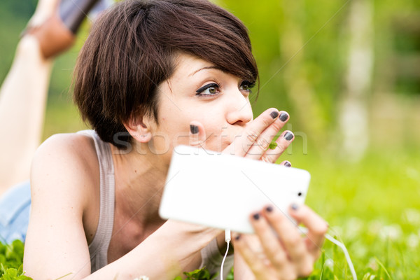Stock photo: Young woman relaxing outdoors listening to music