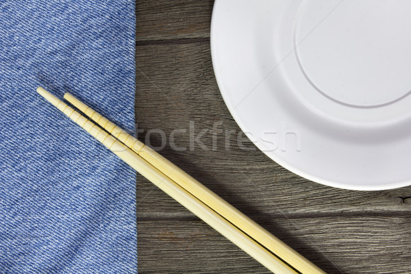 wood background plates, chopsticks and spoons on blue jeans text Stock photo © Gloszilla