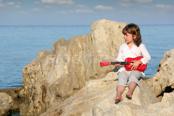 Stock photo: little girl with guitar sitting on rock