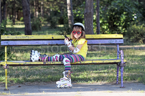 little girl with roller skates sitting on bench and listening mu Stock photo © goce