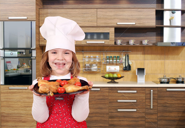 happy little girl cook hold dish with chicken drumstick in kitch Stock photo © goce