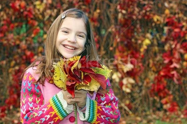 Stock photo: happy little girl holding colorful autumn leaves