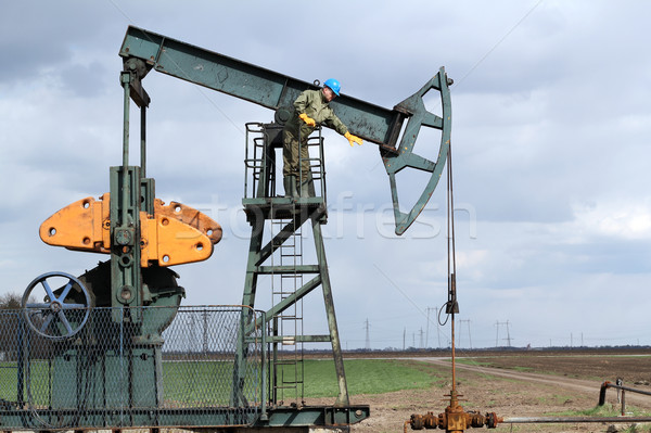 Stock photo: oil worker standing at pump jack