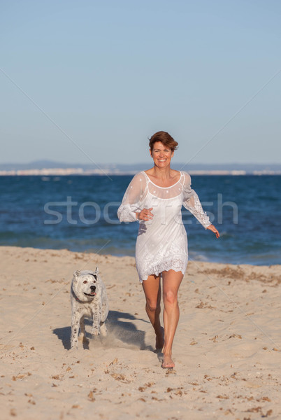 woman running on beach with pet dog Stock photo © godfer