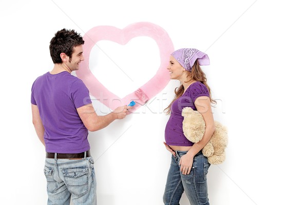 Young couple, husband and pregnant wife painting nursery wall. Stock photo © godfer